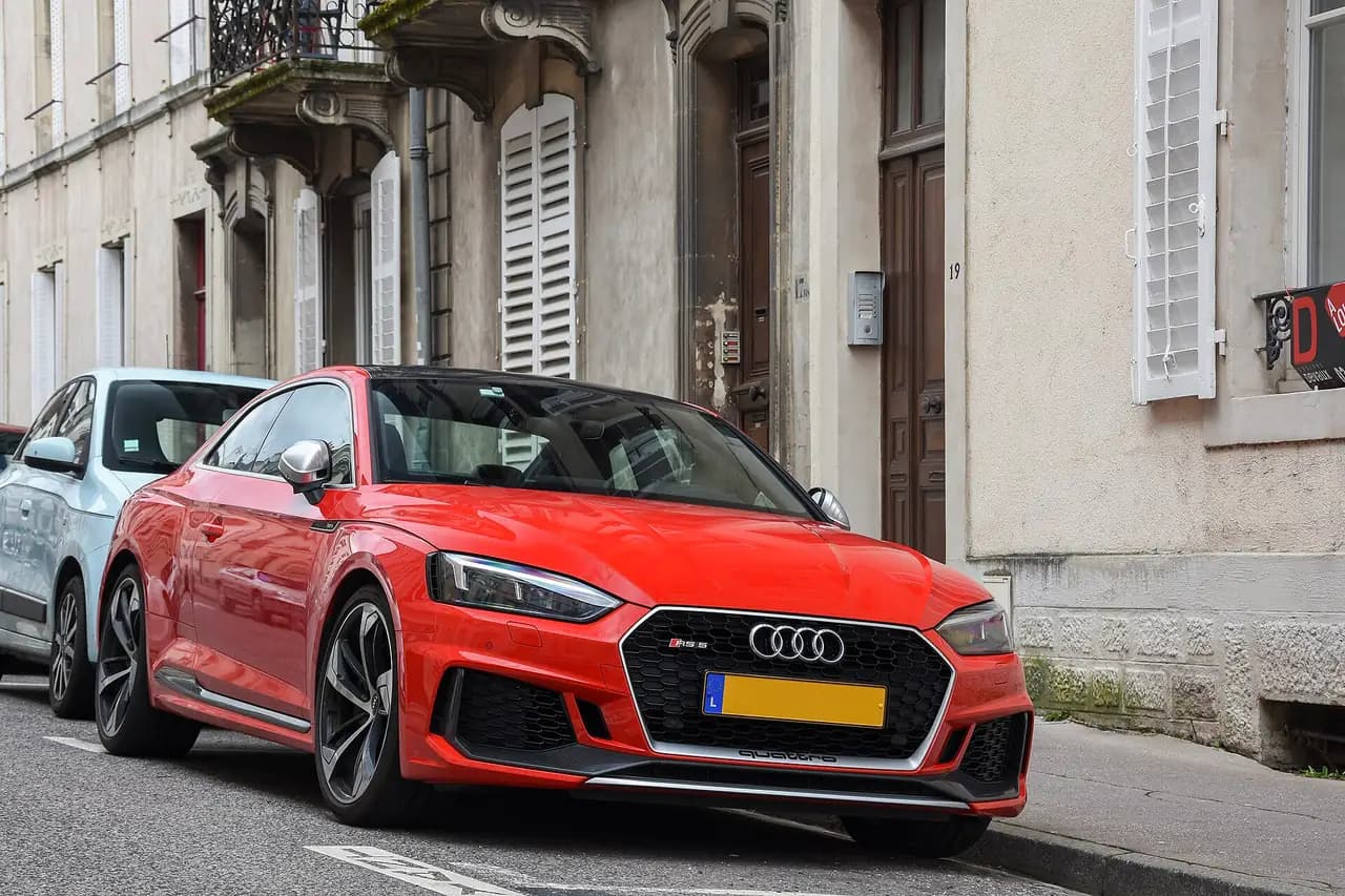Red Audi RS5 Coupé (B9, pre-facelift) parked on a street, front three-quarter view