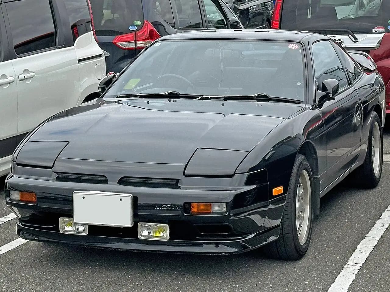 Black Nissan 180SX (RS13 zenki) hatch, pop-up headlights down, front three-quarter view