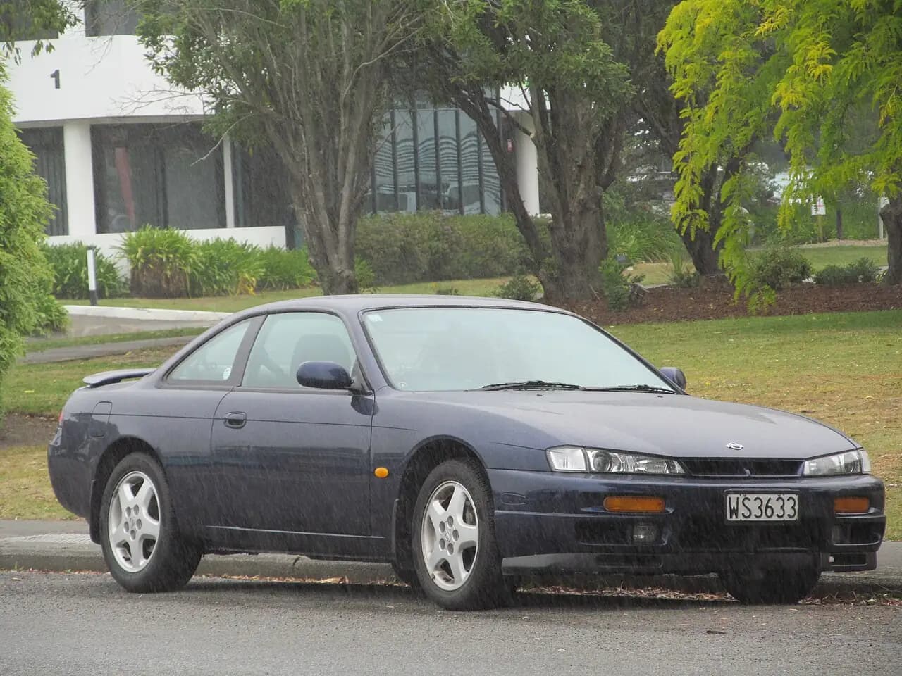 Dark blue 1997 Nissan 200SX (S14a) coupe parked on a street in the rain, front three-quarter view