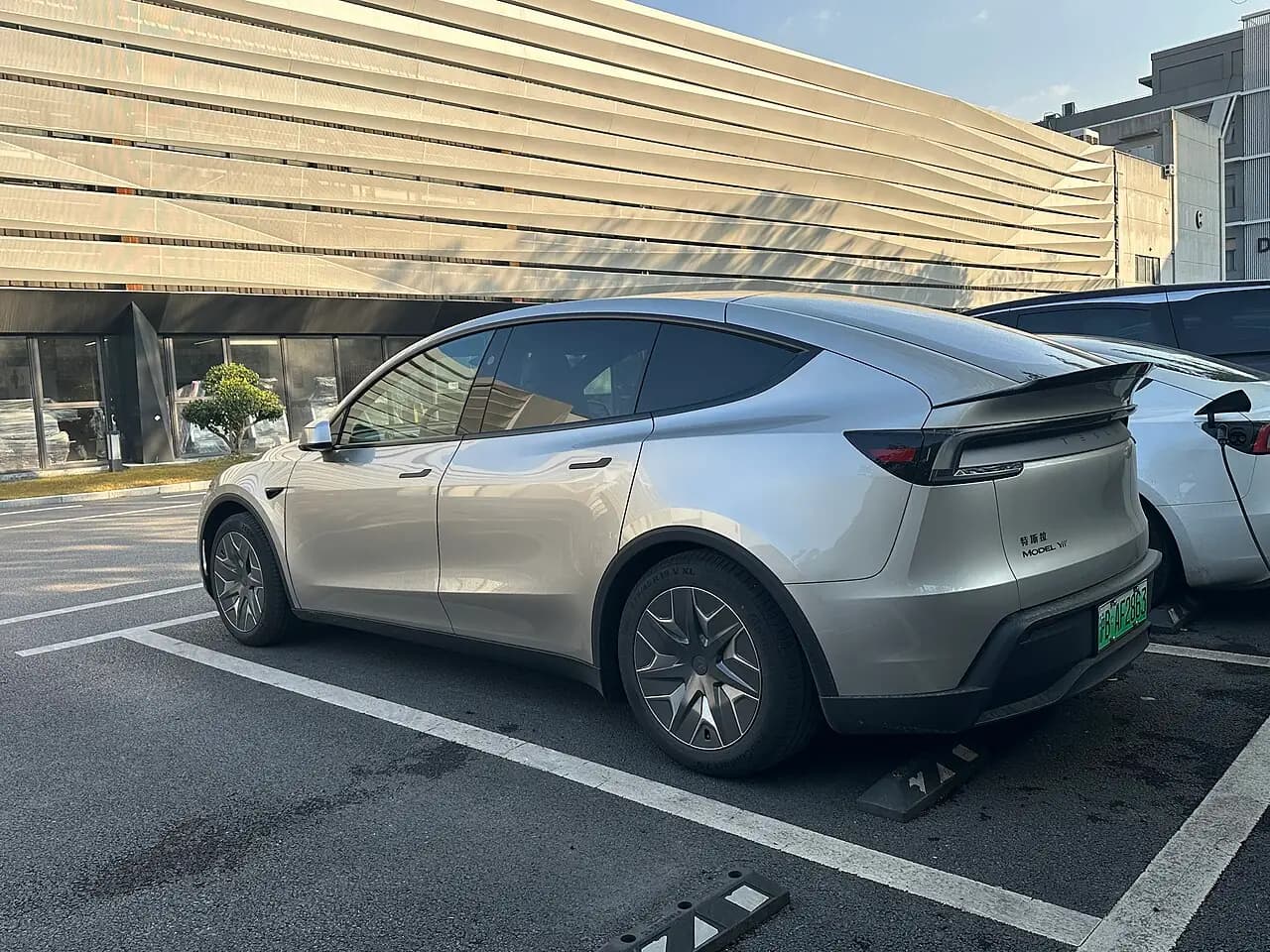 Silver Tesla Model Y L six-seater (Juniper), rear three-quarter view in a car park
