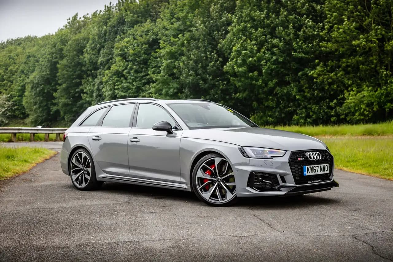 Grey Audi RS4 Avant (B9, pre-facelift) in a tree-lined car park, front three-quarter view