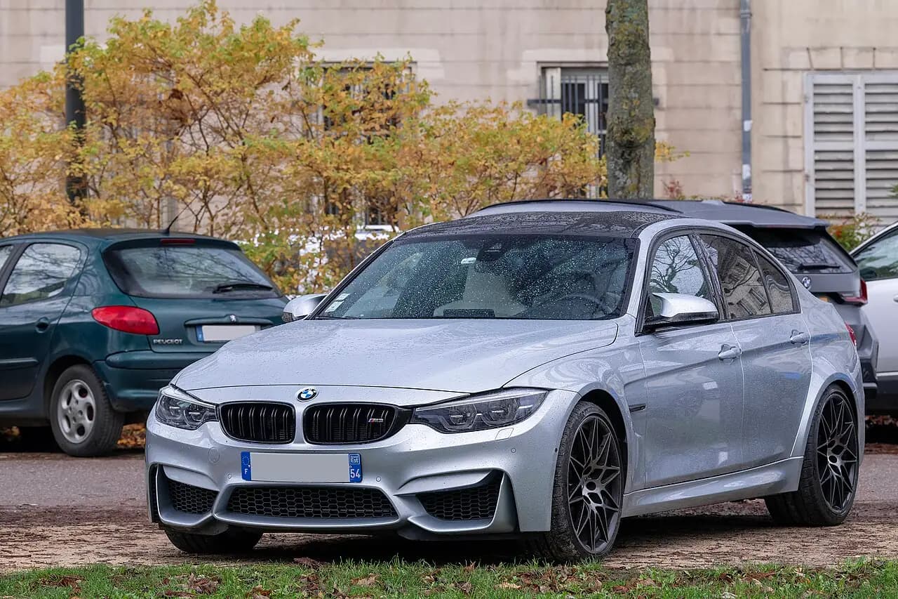 Silver BMW M3 Competition (F80 LCI) sedan parked on a street, front three-quarter view