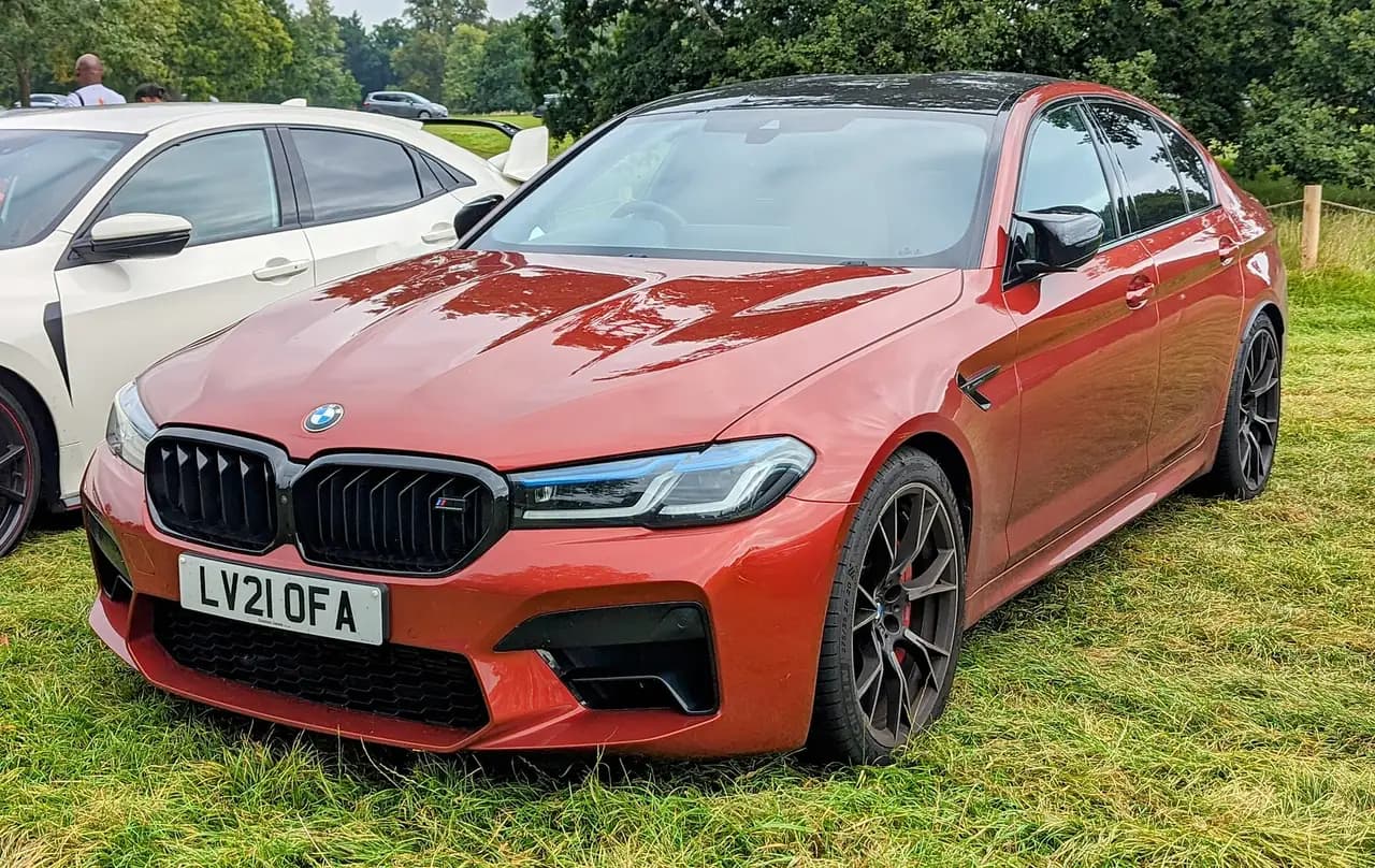 Orange-red 2021 BMW M5 Competition (F90 facelift) sedan, front three-quarter view